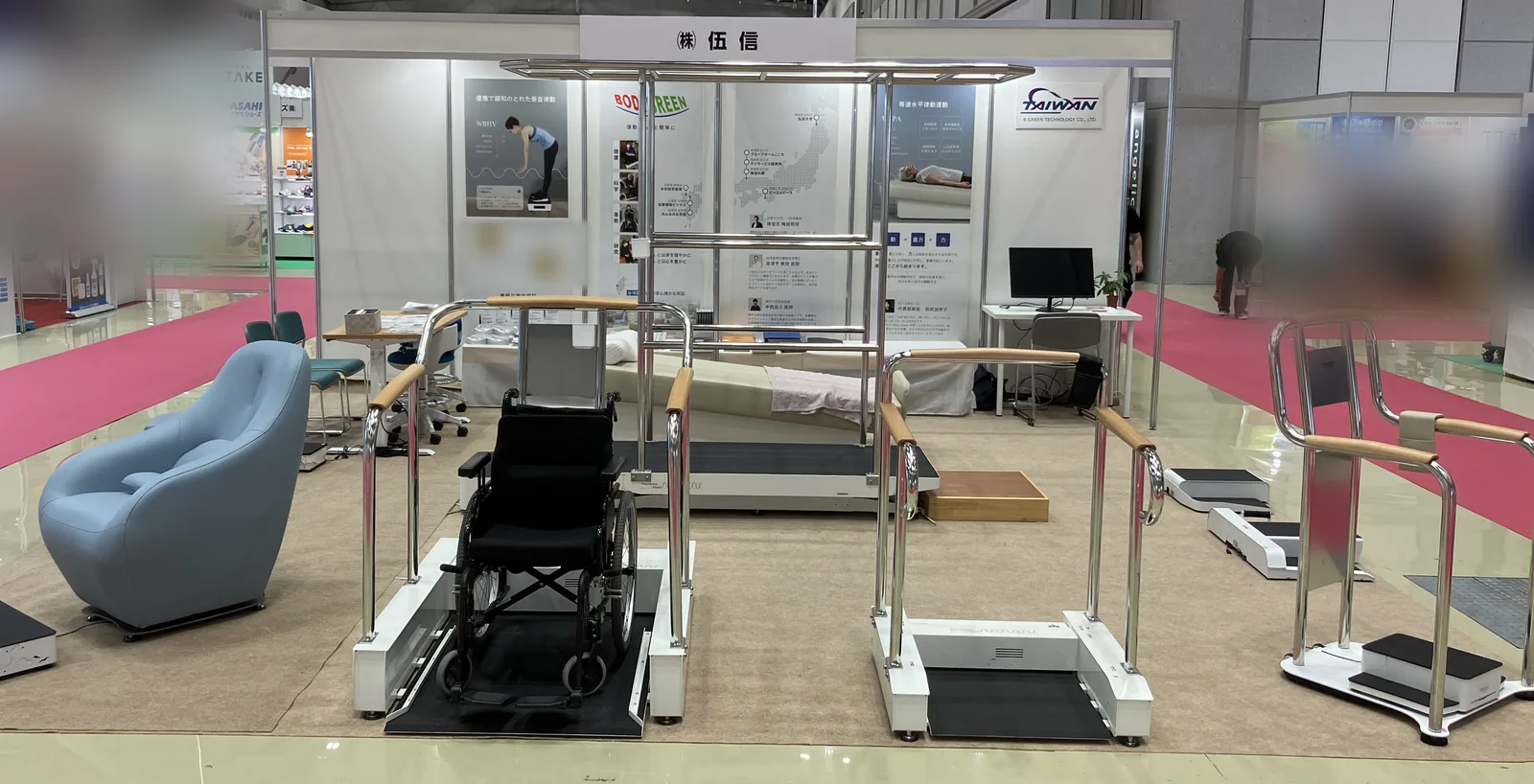 2025年の展示会での株式会社伍信のブース。車椅子のまま乗れる台やチェア型の機種が並んでいる